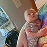 baby, blur, car_seat, casual, chair, colorful_clothing, door_frame, furniture, hand, holding, home, indoor, infant, light_switch, newborn, person, skin, tie_dye, wall, wooden_floor