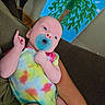 Naomi is registered to the contest to win money with this photo: baby, pacifier, tie_dye, onesie, infant, arm, couch, painting, tree, leaves, blue_sky, indoor, person, child, colorful, relaxing, portrait, skin, hand, furniture