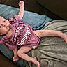 baby, infant, onesie, purple_clothing, person, lap, cushion, fabric, indoor, skin, face, hand, foot, newborn, cute, lying_down, relaxed, small, child, human