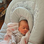 Naomi is registered to the contest to win money with this photo: newborn, baby, sleeping, blanket, baby_seat, floral_clothing, soft_toys, indoors, natural_light, peaceful, infant, cushion, pink, cozy, resting, portrait, cute, child, comfort, household