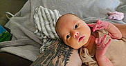 Naomi is registered to the contest to win money with this photo: newborn, baby, tattoo, arm, blanket, striped_cloth, skin, infant, person, portrait, indoor, resting, cute, small_hands, expression, closeup, human, relaxing, casual, comfort