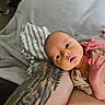 newborn, baby, tattoo, arm, blanket, striped_cloth, skin, infant, person, portrait, indoor, resting, cute, small_hands, expression, closeup, human, relaxing, casual, comfort