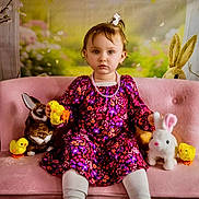 Hadley is registered to the contest to win money with this photo: child, toddler, girl, pink_sofa, floral_dress, necklace, stuffed_bunny, plush_toy, toy_chick, hair_clip, pastel_background, portrait, sitting, eyes, expressionless, white_tights, easter_theme, decorative_bunny, soft_lighting, indoor_photography
