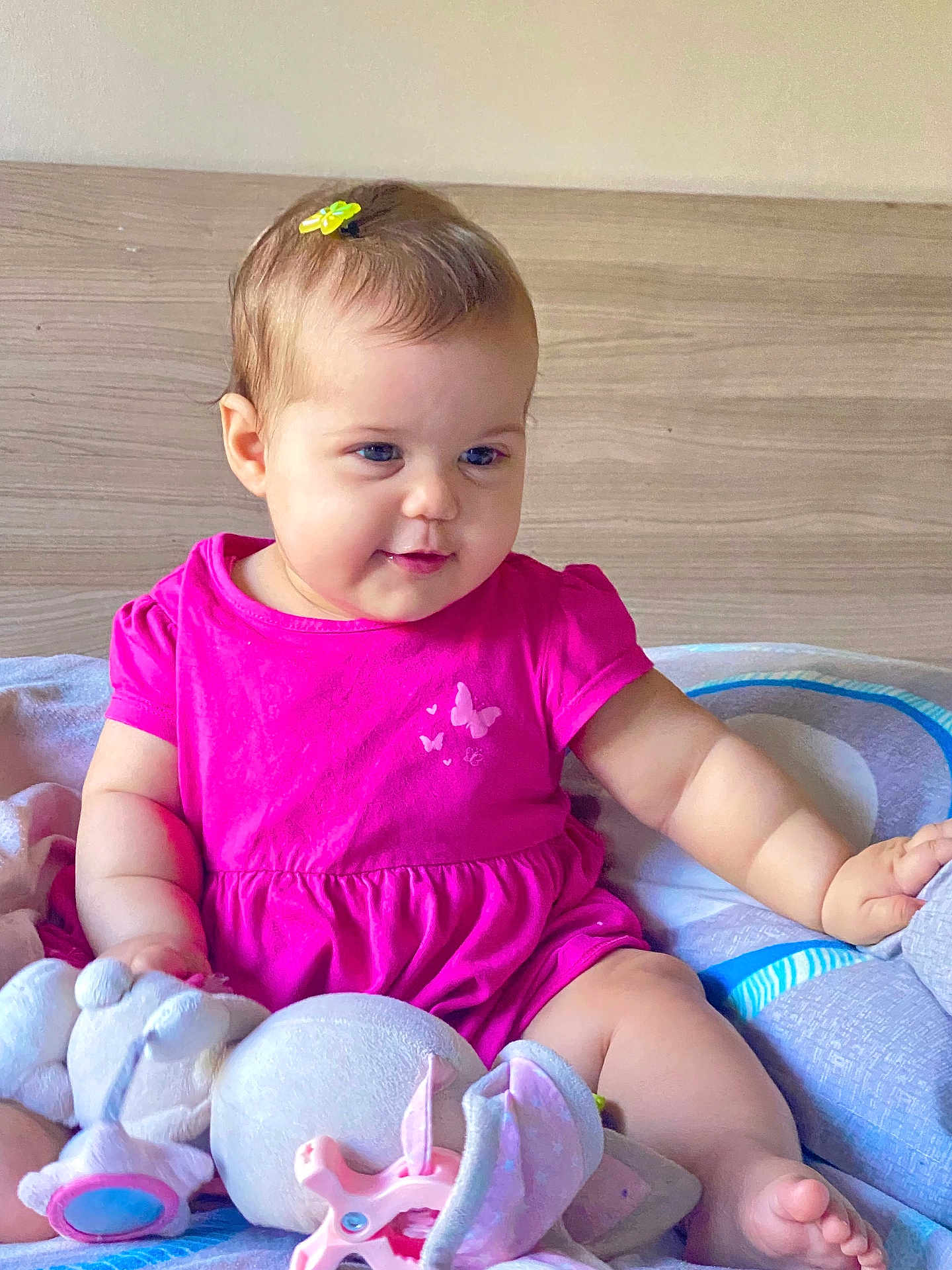 Razane a rejoint le concours — aidez-le/la à gagner de superbes lots ! baby, bed, blanket, child, chubby_cheeks, cute, foot, hair_clip, happy, head, indoor, infant, person, pink_dress, seated, skin, smiling, soft_toys, stuffed_animal, toy