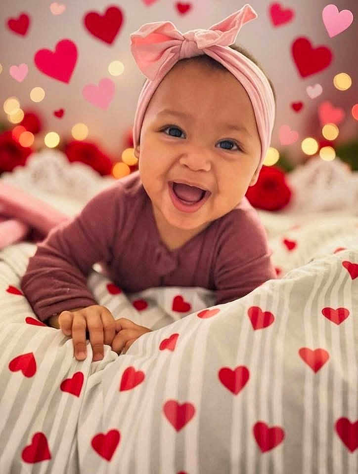 Violet is registered to the contest to win money with this photo: baby, infant, child, smile, headband, bow, hearts, bokeh, blanket, bed, hand, portrait, closeup, happy, giggling, eyes, mouth, cute, pink, red_hearts