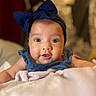 baby, infant, child, portrait, close_up, face, wide_eyes, looking_at_camera, bow, headband, blue_clothing, denim, blanket, bed, indoors, soft_lighting, cozy, sitting, cute, photography