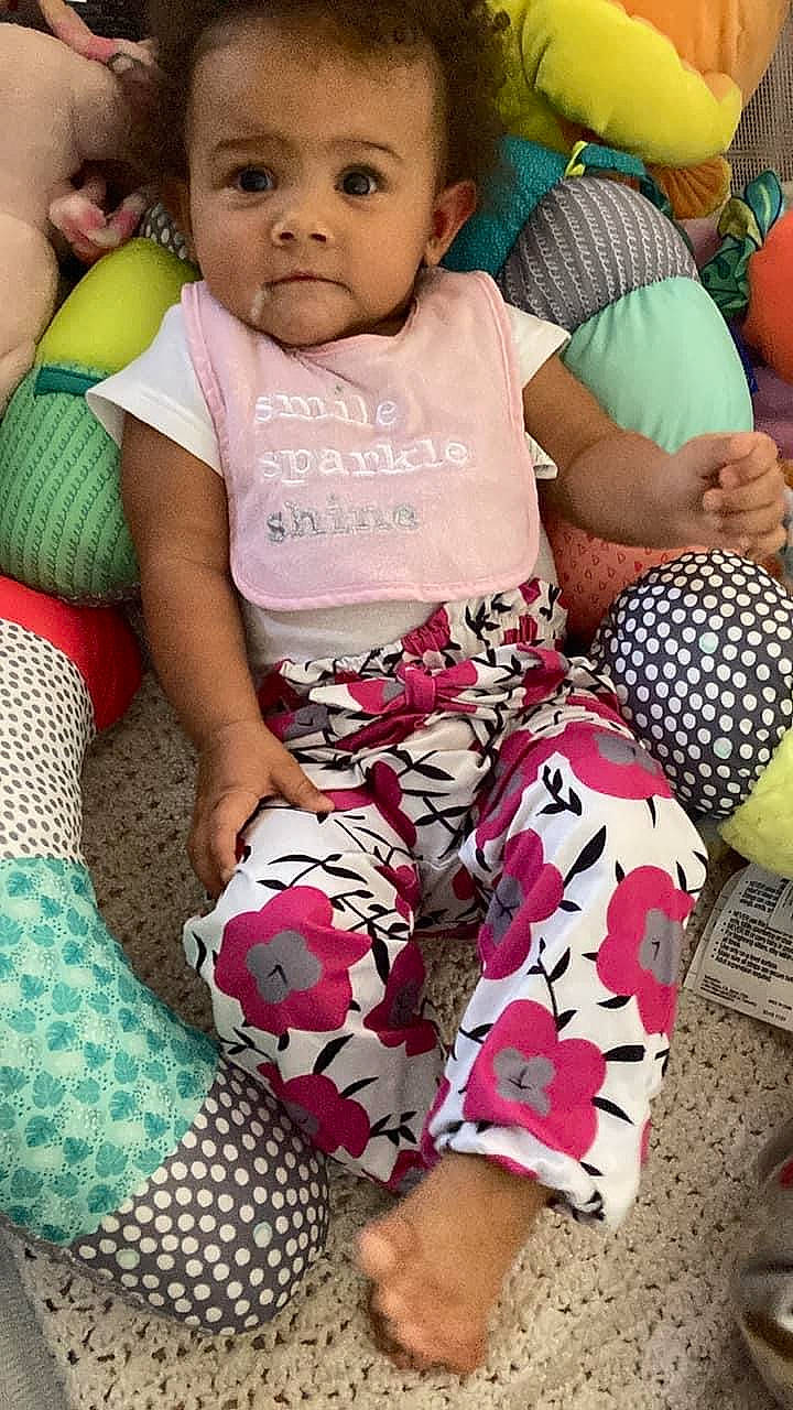 Mariana is registered to the contest to win money with this photo: baby, baby_toddler_clothing, cheek, child, comfort, fun, green, happy, human_leg, knee, leg, leisure, linens, pattern, people, person, shorts, sitting, skin, thigh