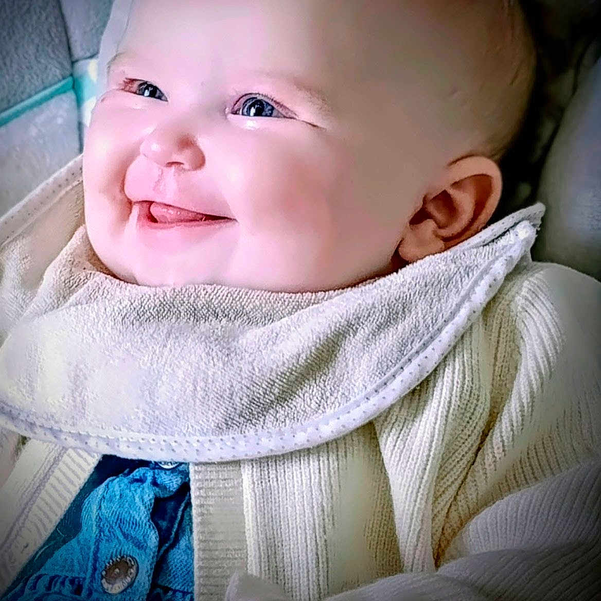Kaaly participe au concours pour gagner de l'argent avec cette photo : baby, bib, blue_clothing, cheeks, child, closeup, cozy, cute, face, happy, head, indoor, infant, knitted_sweater, person, portrait, smile, tongue, warm_clothing, young