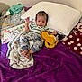 Uzi is registered to the contest to win money with this photo: baby, bed, blanket, child, clothing, cozy, face, foot, hand, indoor, lion, pants, pillow, plush_toy, polka_dot_blanket, purple, sleepwear, striped_shirt, toddler, white