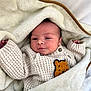 Alessio a rejoint le concours — aidez-le/la à gagner de superbes lots ! baby, blanket, knitted_sweater, bear_patch, cozy, infant, soft_texture, cute, hands, face, newborn, wrapped, warm, sleeping_area, child, portrait, indoors, comfort, clothing, resting