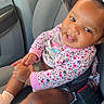 Nai Saiah is registered to the contest to win money with this photo: baby, child, infant, smiling, happy, car_seat, car, vehicle, portrait, indoor, seated, floral_clothing, pink_clothing, hair_bow, pacifier, pacifier_clip, seatbelt, hands, socks, closeup