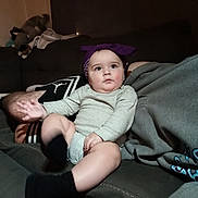 Kayson joined the competition — help win amazing prizes! baby, infant, child, couch, headband, purple, onesie, socks, living_room, furniture, person, seated, indoor, cute, chubby_cheeks, casual_clothing, soft_lighting, curious_expression, plush_toys, relaxing