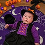 baby, bat_toy, black_dress, child, costume, cute, festive, floor, halloween_costume, halloween_decorations, holiday, indoors, infant, moon_pattern, portrait, pumpkins, purple_clothing, spiderweb_pattern, stars, witch_hat