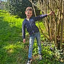 boy, branches, child, garden, grass, greenery, ground, hedge, jacket, jeans, nature, outdoor, playful, portrait, pose, smiling, sneakers, sunlight, tree, young_person