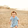child, toddler, beach, sand, curly_hair, blue_outfit, sunset, outdoor, portrait, barefoot, young_child, summer, nature, cute, baby, walking, sunlight, playful, vacation, holiday