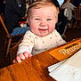baby, infant, smiling, happy, toddler, restaurant, wooden_table, menu, hand, high_chair, person, adult, background_people, chair, clothing, portrait, candid, dining, chubby_cheeks, eyes