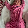 baby, sleeping, pink_onesie, polka_dots, blanket, pacifier, heart_pattern, infant, cozy, cute, child, soft_texture, resting, indoors, portrait, newborn, peaceful, fabric, wearing_clothes, lying_down