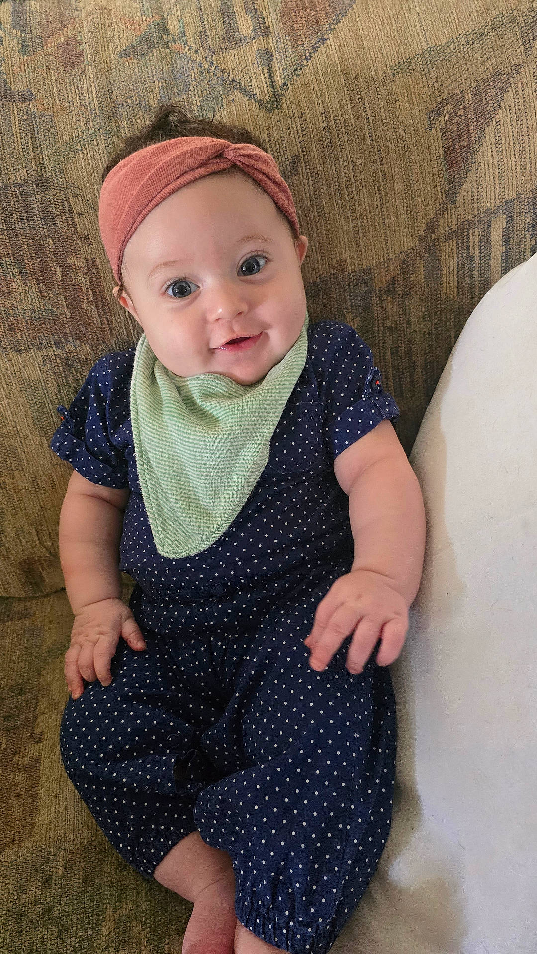 Rukia joined the competition — help win amazing prizes! baby, blue_clothing, casual_wear, child, chubby_arms, comfortable, couch, cute, green_bib, happy, headband, indoors, infant, patterned_fabric, polka_dot, portrait, sitting, small_hands, smiling, young_child