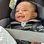 baby, car_seat, child, smiling, happy, infant, seatbelt, clothing, striped, button, fabric, safety, toy, hand, closeup, cute, indoors, person, face, seat