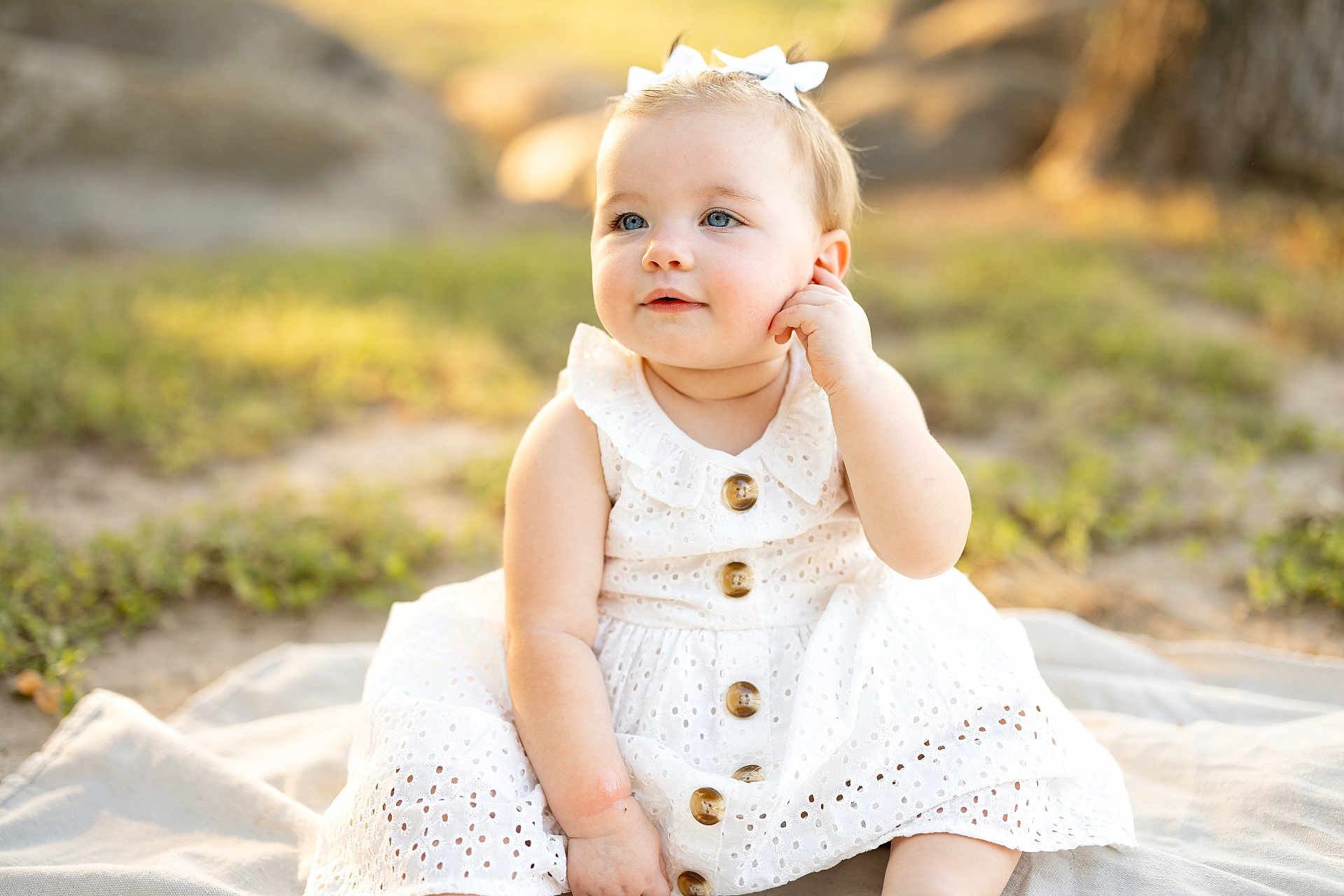 Brinsley joined the competition — help win amazing prizes! baby, child, white_dress, bow, outdoor, sunlight, blanket, sitting, cute, portrait, infant, young_child, nature, grass, face, blue_eyes, happy, soft_light, summer, youth