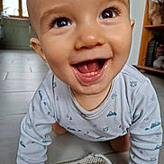 Charly participe au concours pour gagner de l'argent avec cette photo : baby, smiling, crawling, indoor, onesie, floor, happy, child, face, eyes, mouth, tongue, long_sleeve, patterned_clothing, home, kitchen, tile_floor, carpet, person, cute