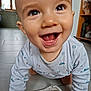 baby, smiling, crawling, indoor, onesie, floor, happy, child, face, eyes, mouth, tongue, long_sleeve, patterned_clothing, home, kitchen, tile_floor, carpet, person, cute