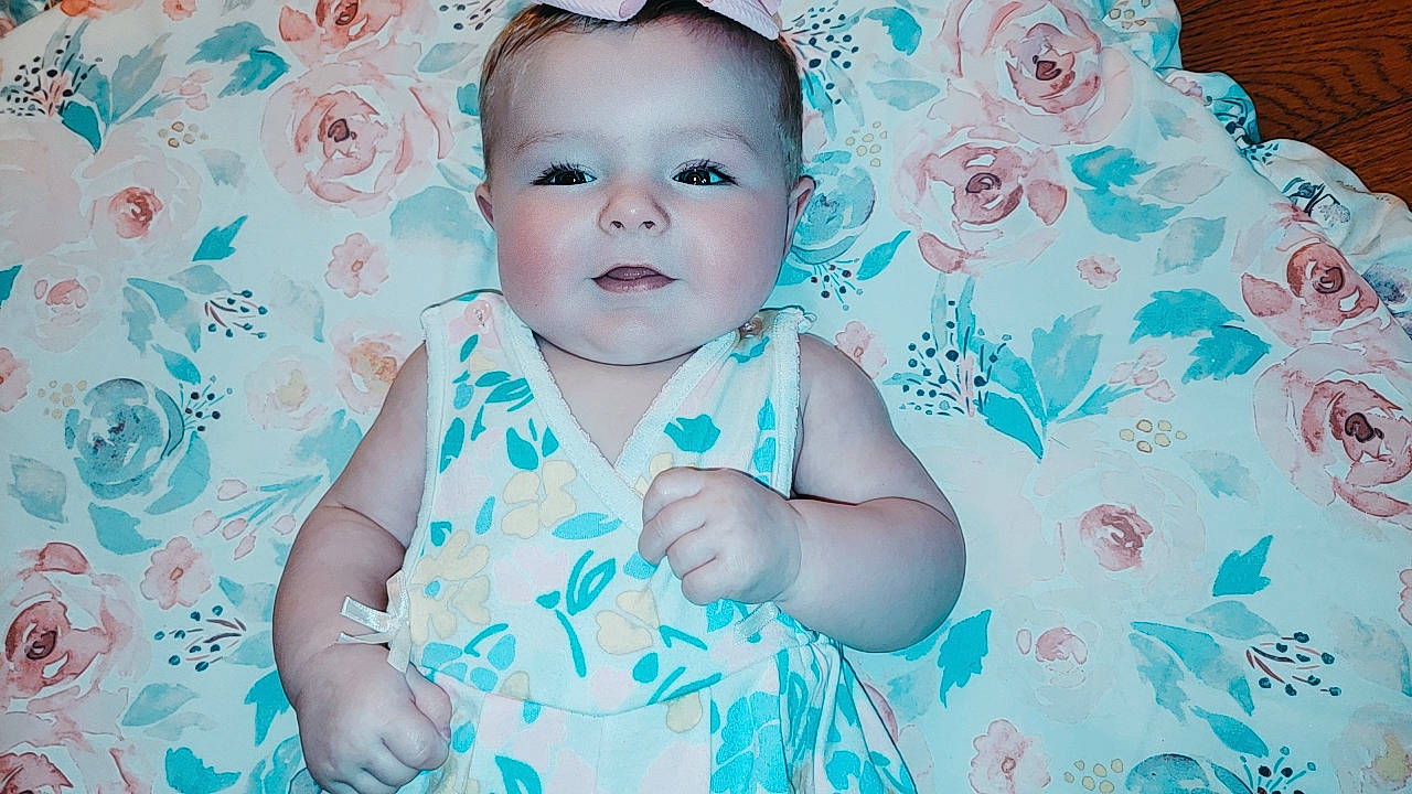 Magnolia is registered to the contest to win money with this photo: aqua, azure, baby, baby_toddler_clothing, cheek, child, eyelash, flash_photography, fun, grass, happy, iris, linens, pattern, person, pink, portrait_photography, skin, sleeve, textile
