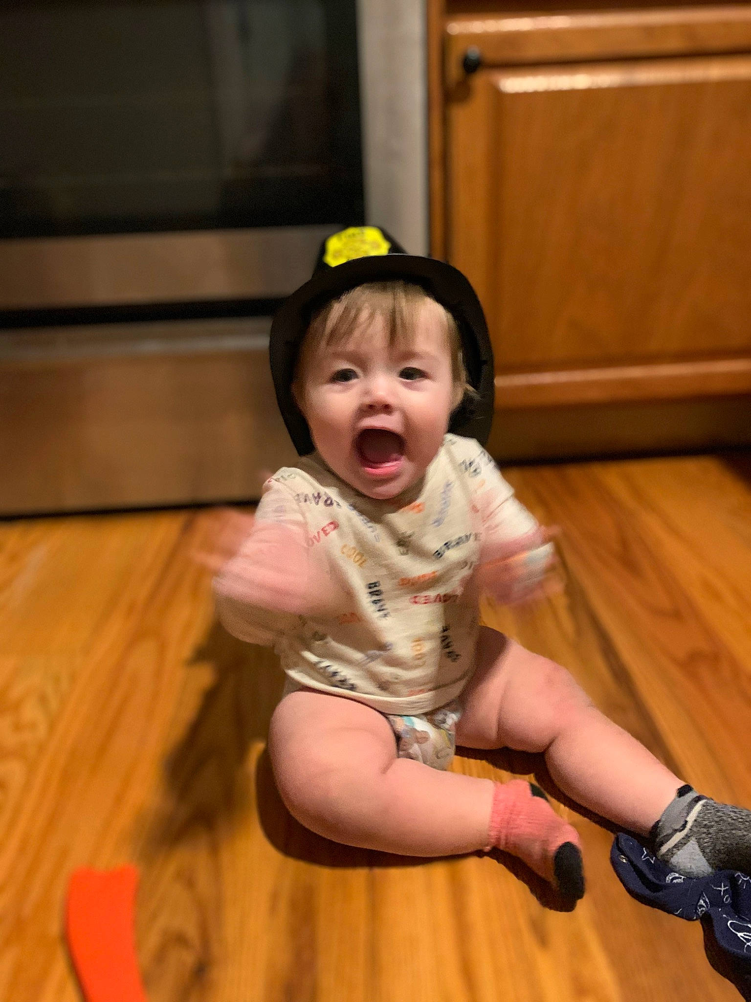 Griffin is registered to the contest to win money with this photo: baby, baby_toddler_clothing, eye, floor, flooring, fun, happy, hardwood, human_leg, leg, person, sandal, shoe, skin, smile, sneakers, thigh, thumb, toddler, wood