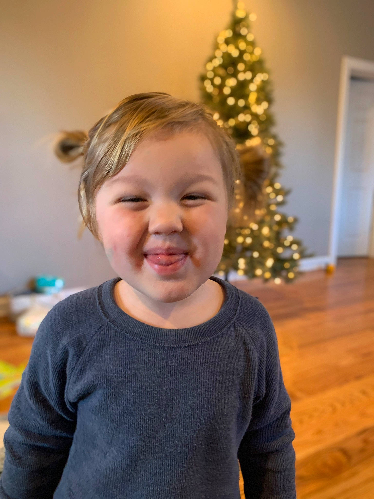 Julian is registered to the contest to win money with this photo: baby_toddler_clothing, cheek, christmas, christmas_decoration, christmas_ornament, christmas_tree, door, event, fun, hair, happy, holiday, holiday_ornament, joy, ornament, person, sleeve, smile, standing, toddler