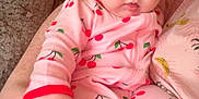 Everly is registered to the contest to win money with this photo: baby, child, onesie, pink, cherry_pattern, couch, hand, person, indoor, portrait, infant, clothing, cute, expression, face, sitting, texture, fabric, human, young