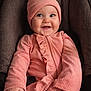 Everly joined the competition — help win amazing prizes! baby, pink_outfit, hat, pom_pom, smile, happy, child, face, cushion, chair, indoors, portrait, cozy, warm_clothing, infant, cute, hands, seated, young_child, apparel