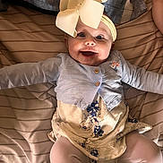 Amelia joined the competition — help win amazing prizes! baby, infant, headband, bow, smile, happy, lying_down, bed, blanket, cardigan, dress, floral_pattern, tights, chubby_cheeks, wide_eyes, portrait, indoors, cute, fabric, hands_up