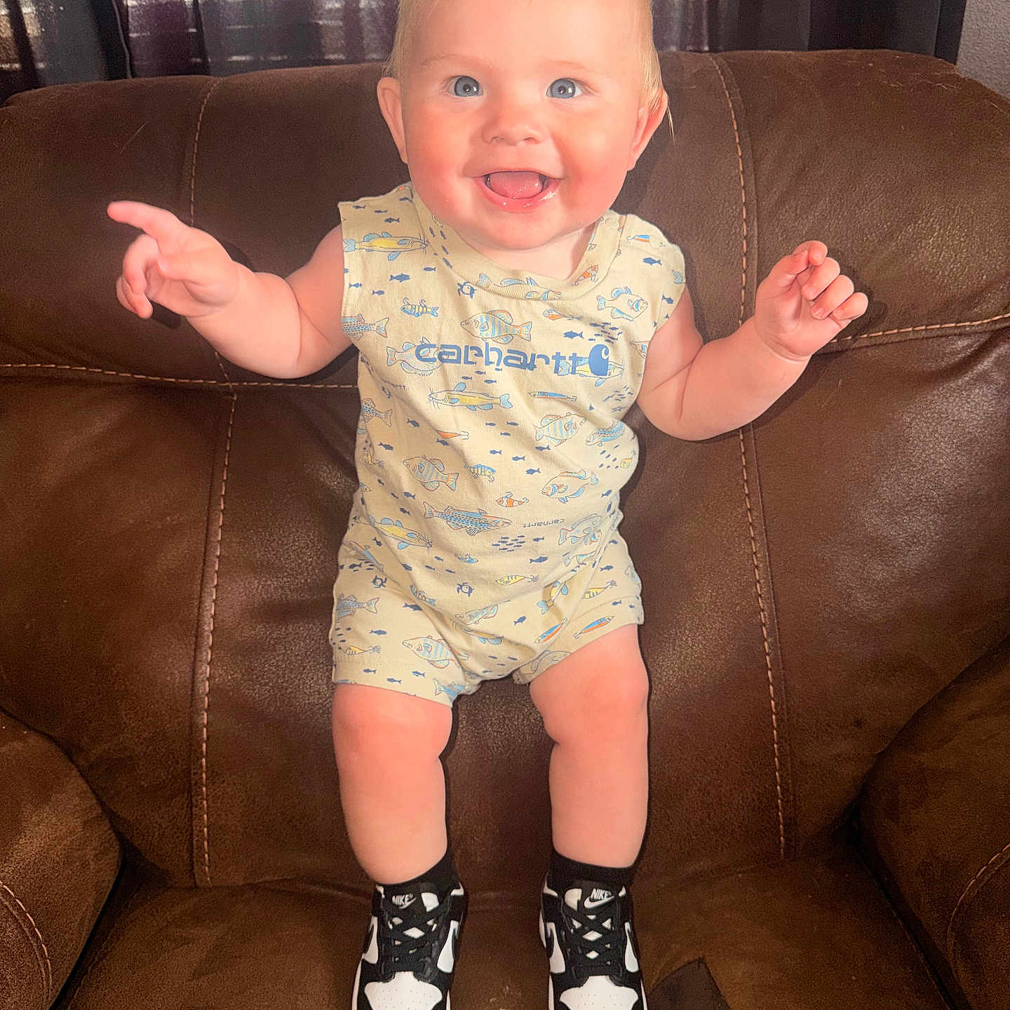 Leeland is registered to the contest to win money with this photo: baby, child, smile, happy, sitting, armchair, clothing, romper, sneakers, shoes, indoor, person, cute, blond_hair, blue_eyes, furniture, portrait, baby_clothes, feet, joy