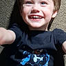 child, boy, smiling, tshirt, venom, carpet, lying_down, happy, casual_clothing, portrait, indoor, young, short_hair, light_skin, blue_eyes, graphic_tee, childhood, playful, joyful, closeup