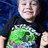 blue_blanket, boy, casual, child, closeup, clothing, cute, happy, hulk, indoor, joyful, laying_down, marvel, person, portrait, smile, spiderman, superhero, tshirt, young