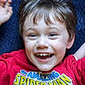 child, boy, smile, happy, red_shirt, spiderman, tshirt, face, hair, lying_down, portrait, casual, young, cute, joyful, indoor, closeup, expression, cheerful, person
