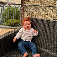 Saja a rejoint le concours — aidez-le/la à gagner de superbes lots ! baby, child, smiling, outdoor, chair, woven_chair, headband, orange_headband, jeans, white_cardigan, barefoot, railing, stone_wall, building, sky, greenery, portrait, happy, cute, sitting