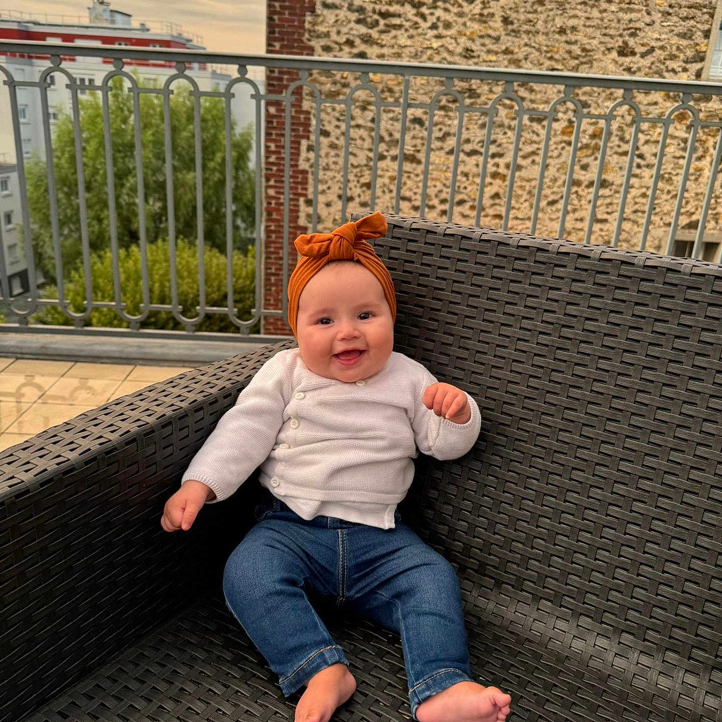 Saja a rejoint le concours — aidez-le/la à gagner de superbes lots ! baby, barefoot, building, chair, child, cute, greenery, happy, headband, jeans, orange_headband, outdoor, portrait, railing, sitting, sky, smiling, stone_wall, white_cardigan, woven_chair