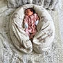 newborn, baby, sleeping, pink_clothing, pillow, animal_print, blanket, bed, soft_texture, cozy, infant, resting, cute, small, indoors, comfort, peaceful, child, nursery, relaxation