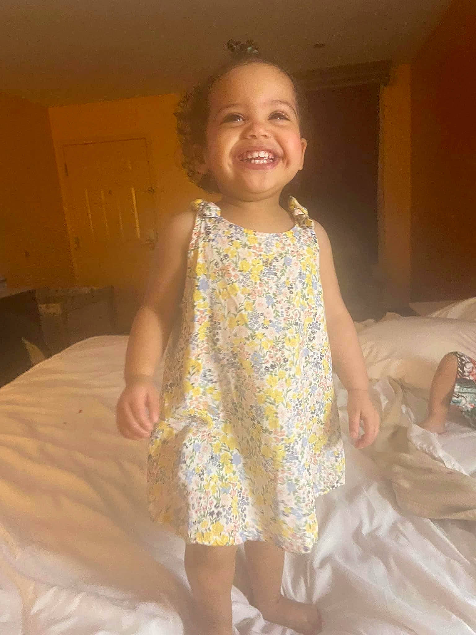 Kenzleigh is registered to the contest to win money with this photo: arm, baby_toddler_clothing, barefoot, comfort, dress, floor, flooring, fun, gesture, hand, happy, human_body, human_leg, joy, linens, person, shoulder, skin, sleeve, smile
