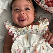 Sage joined the competition — help win amazing prizes! baby, child, tongue_out, smiling, cute, infant, clothing, patterned_dress, fish_pattern, pillow, floral, soft_surface, happy, playful, portrait, indoors, skin, face, hand, lying_down