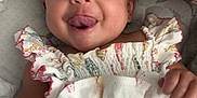 Sage joined the competition — help win amazing prizes! baby, child, tongue_out, smiling, cute, infant, clothing, patterned_dress, fish_pattern, pillow, floral, soft_surface, happy, playful, portrait, indoors, skin, face, hand, lying_down