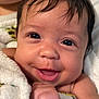 Sage is registered to the contest to win money with this photo: baby, close_up, smiling, face, towel, skin, infant, child, cute, portrait, happy, hand, dark_hair, indoors, expression, young, person, human, cheerful, wrapping