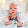 baby, infant, smiling, blue_eyes, headband, bow, striped_clothing, ruffles, cute, happy, lying_down, blanket, soft, portrait, child, person, indoors, bright, closeup, joyful