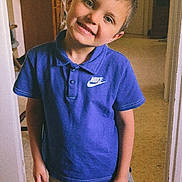 Ninyo a rejoint le concours — aidez-le/la à gagner de superbes lots ! child, boy, smiling, blue_shirt, nike, shorts, indoor, home, plant, furniture, door, floor, portrait, happy, casual_clothing, standing, head_tilt, person, young, cute