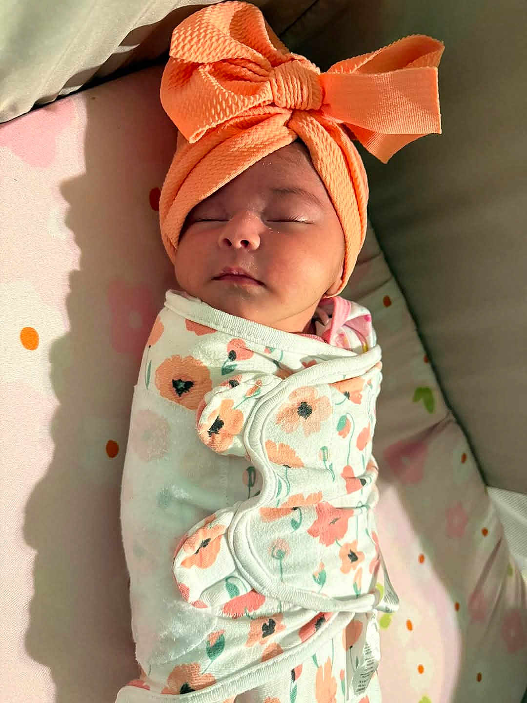 Isabella is registered to the contest to win money with this photo: baby, sleeping, headband, orange, blanket, floral, swaddle, infant, cute, peaceful, soft_light, indoors, closeup, portrait, newborn, face, wrapped, child, resting, adorable