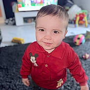 Joey is registered to the contest to win money with this photo: toddler, child, red_sweater, mickey_mouse, smiling, indoor, carpet, toys, living_room, television, playful, cute, person, young_child, happy, portrait, standing, floor, casual_clothing, home
