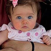 Lucca is registered to the contest to win money with this photo: baby, child, person, holding, pink_bow, pink_dress, blue_eyes, face, closeup, portrait, adult, sunglasses, hand, skin, hair, outdoor, table, menu, expression, tender_moment