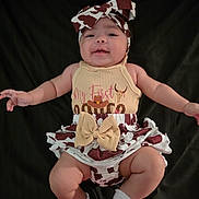 Jayleen is registered to the contest to win money with this photo: baby, infant, child, smiling, headband, bow, cow_print, outfit, socks, cute, portrait, happy, lying_down, clothing, skin, arms, legs, expression, studio, black_background
