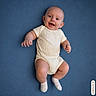 Atreus joined the competition — help win amazing prizes! baby, child, infant, smiling, portrait, lying_down, blue_background, cream_outfit, onesie, socks, happy, face, hands, arms, legs, indoor, studio, photography, closeup, ai_generated